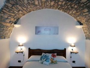 1 dormitorio con 1 cama con pared de piedra en Agriturismo Al Pagan, en Pigna