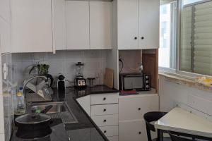 a kitchen with white cabinets and a sink and a microwave at rooftop studio 70 meters in Netanya