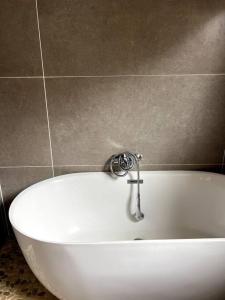 a white bath tub in a bathroom with a tile wall at South Coast Suburban Escape in Kingsburgh