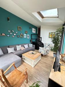 ein Wohnzimmer mit einem Sofa, einem Tisch und einem Klavier in der Unterkunft Spacieuse maison - Petite mer in Riantec