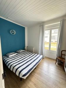 Schlafzimmer mit einem Bett mit blauer Wand in der Unterkunft Spacieuse maison - Petite mer in Riantec