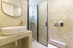 a bathroom with a sink and a shower with a mirror at Sani Bliss by halu!, 2-BD villa with private garden in Sani Beach