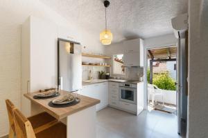 a kitchen with white cabinets and a table with plates on it at Sani Bliss by halu!, 2-BD villa with private garden in Sani Beach