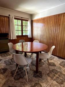 ein Esszimmer mit einem Holztisch und weißen Stühlen in der Unterkunft Departamento Del Centro Primer Piso in El Bolsón