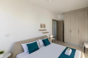 a bedroom with a large white bed with blue pillows at Accomoteleia Blue Villa in Protaras