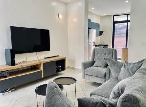 uma sala de estar com um sofá e duas cadeiras e uma televisão em LUXURYSTAY-CATION em Kigali