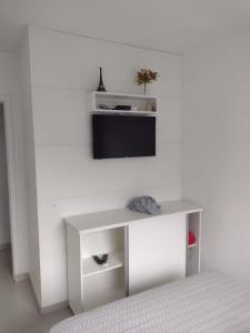 Biały stół z telewizorem na ścianie w obiekcie Casa de praia na Gamboa - Garopaba SC w mieście Garopaba