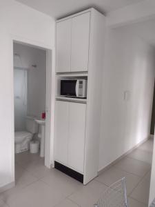 a white kitchen with a microwave on a counter at Casa de praia na Gamboa - Garopaba SC in Garopaba