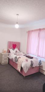a bedroom with a pink bed and a window at BS Lodge in Mitcham