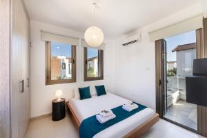 a bedroom with a bed and a tv and windows at Accomoteleia Blue Villa in Protaras