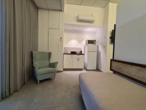 a living room with a chair and a refrigerator at White Elephant - יחידת סטודיו מקסימה צמודה לשוק מחנה יהודה in Jerusalem