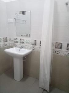 a white bathroom with a sink and a mirror at Billiards villa in Trincomalee