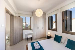 a bedroom with a bed and windows and a desk at Accomoteleia Blue Villa in Protaras