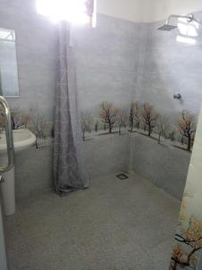a bathroom with a shower with trees on the wall at Billiards villa in Trincomalee