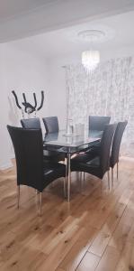 comedor con mesa de cristal y sillas negras en BS Lodge, en Mitcham