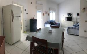 cocina y sala de estar con mesa y nevera en Comfort Home, en Capoterra