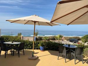 a patio with tables and chairs and an umbrella at Un Thé Au Bout Du Monde in Mirleft