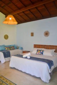 a bedroom with two beds and a ceiling at Vila Sol Chalés in Pôrto de Pedras