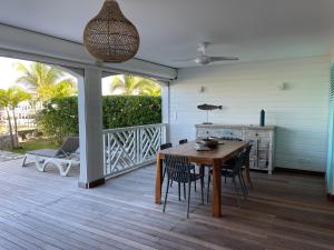 eine Veranda mit einem Holztisch und Stühlen auf einer Terrasse in der Unterkunft Princess Mahault - Beachfront - Orient bay - luxury apartment in Orient Bay