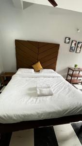 a bedroom with a large white bed with a wooden headboard at Casa Almeida Hotel in Candolim