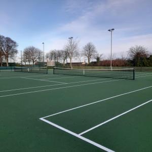 a tennis court with two tennis nets on it at Riverbank Apartments in Nairn