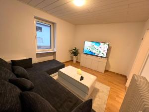 sala de estar con sofá y TV de pantalla plana en Sehr große Ferienwohnung, Apartment in Kaiserslautern WeHome Komfort, en Kaiserslautern