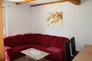 un sofá rojo en una sala de estar con mesa en Ferienhaus Caro, en Federow