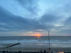a sunset over a beach with a pier and the ocean at Seaside Escapes, Bridlington in Sewerby