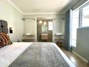 a bedroom with a large bed and a bathroom at Brunia Bay Apartment in Hermanus