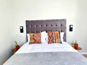a bed with a gray headboard and pillows on it at Brunia Bay Apartment in Hermanus