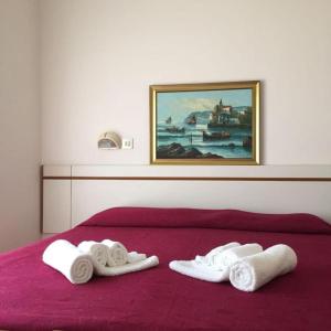 twee handdoeken op een rood bed met een schilderij bij HOTEL ITALIACERVIA Free Breakfast in Cervia