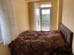 un letto in una camera con finestra e copriletto di ormanın içinde geniş havuzlu triplex villa a Manavgat