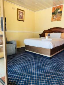 sypialnia z łóżkiem i krzesłem w pokoju w obiekcie Royal Olympia Lodge Lusaka w mieście Lusaka