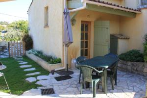 Peymeinade的住宿－Gîte Lou Caillou，庭院配有桌椅和遮阳伞。