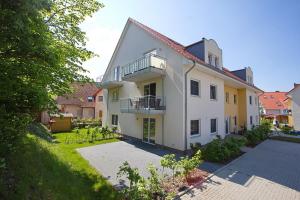 een groot wit huis met een balkon en een tuin bij Ferienwohnung Feelmeer in Rerik