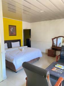Habitación de hotel con cama y silla en Royal Olympia Lodge Lusaka, en Lusaka