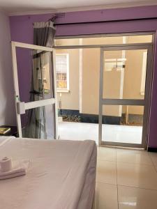 a bedroom with a bed and a sliding glass door at Royal Olympia Lodge Lusaka in Lusaka