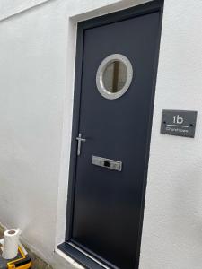 eine blaue Tür mit einem runden Fenster darauf in der Unterkunft Lovely flat, balcony & woodstove, parking close in St. Agnes 