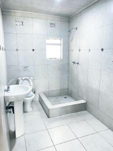a white bathroom with a toilet and a sink at Royal Olympia Lodge Lusaka in Lusaka