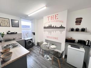 una cocina con una mesa y un cartel en la pared en Cosy Flat by Anfield: 5 Minutes from the Stadium!, en Liverpool