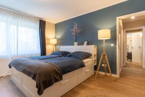 - une chambre avec un grand lit aux murs bleus dans l'établissement Ferienwohnung - Nordisch by Nature, à Ording
