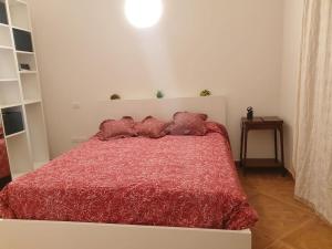 una camera con un letto rosso con due cuscini sopra di L'Olmo vestito a Teramo