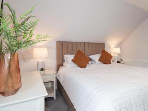 a bedroom with a bed and a vase with a plant at Bonnieview in Lossiemouth