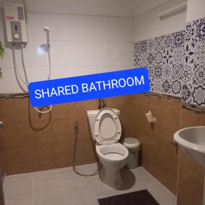 La salle de bains est pourvue d'un panneau indiquant la salle de bains au-dessus des toilettes. dans l'établissement Happy Hostel, à Bangkok