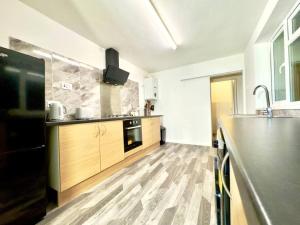 a kitchen with wooden cabinets and a counter top at Spacious Accommodation for Contractors and Families 4 Bedrooms, Sleeps 8, Smart TV, Netflix, Parking, Only 20 Minutes to Birmingham, M6 J9 in Darlaston