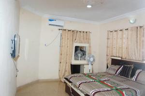 - une chambre avec un lit, un ventilateur et un miroir dans l'établissement Asoro Apartments, à Benin City