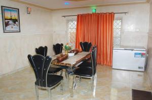 una sala da pranzo con tavolo in legno e sedie nere di Asoro Apartments a Benin City