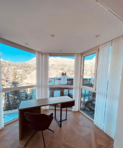 una stanza con tavolo, sedie e ampie finestre di Exclusive Comfy Apartment in Central Crans-Montana a Lens