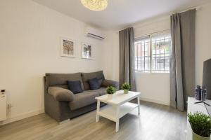 een woonkamer met een bank en een tafel bij Apartamento San Isidro - Elegante y centrico apt. p/5 con Wifi y AC in Alcalá de Henares
