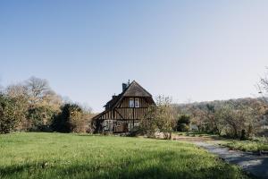 uma casa grande numa colina com um campo de relva em Colombe - Une Maison du Pays d'Auge - Bain nordique em Le Mesnil-Eudes